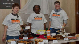 Community fundraisers wearing Malaria No More UK tshirts fundraising money by selling cakes