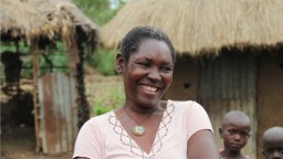 A woman standing outside her home laughing