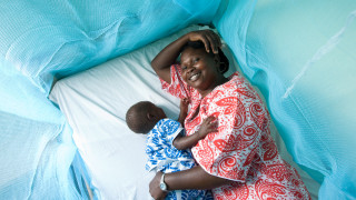 A woman and her child under a mosquito net