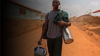 An insecticide sprayer heads to work protecting his community from malaria