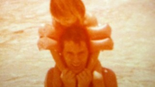 An old photo of a dad with his little girl on his shoulders