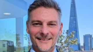 New Managing Director of Malaria No More UK, Gareth Jenkins smiles at the camera. Behind him is the London skyline including the Shard building and a clear blue sky. 