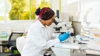 Female scientist looks through microscope